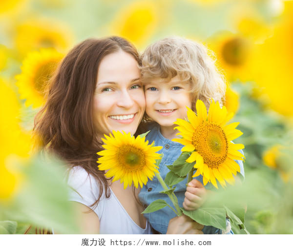 妈妈抱着孩子拿着向日葵葵花在花丛中微笑